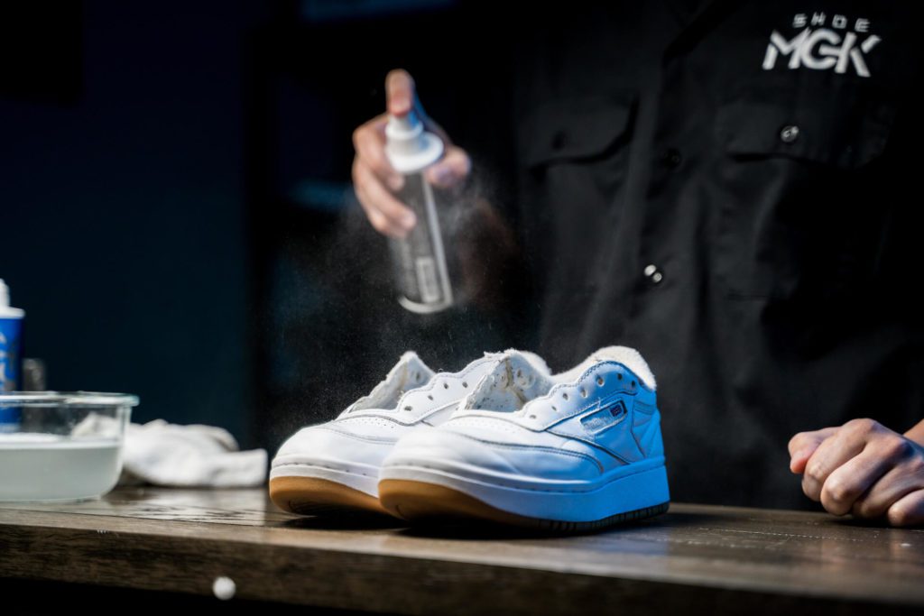 Man sprays white shoes with the Shoe MGK Water and Stain Repellent