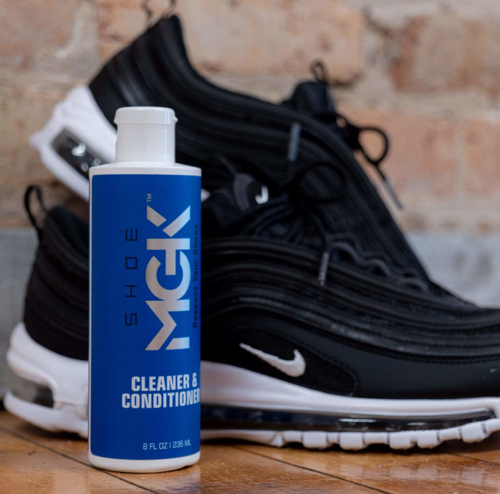 A bottle of Shoe MGK Cleaner and Conditioner next to Air Max 97 shoes