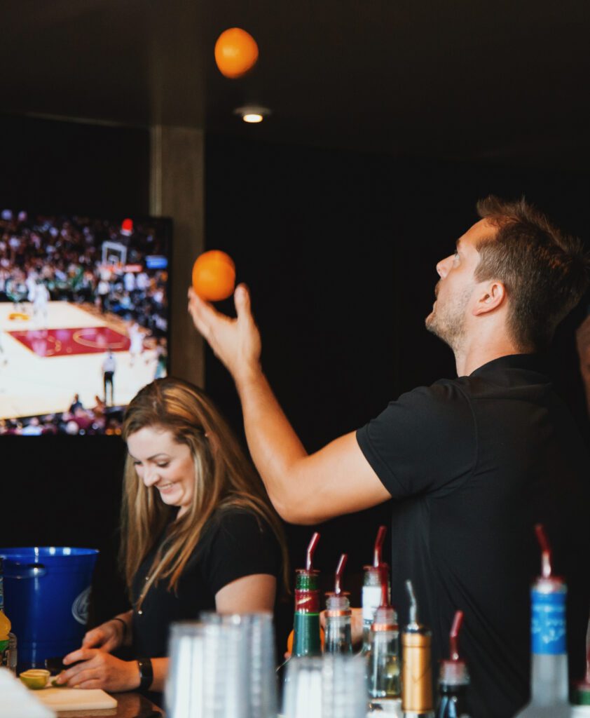 Man juggles oranges behind a bar