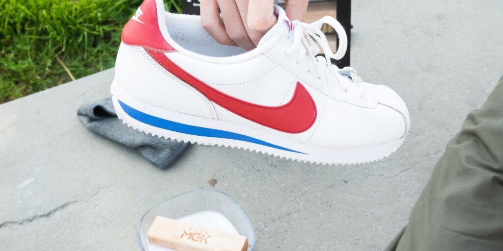 Man holds white, red, and blue Nikes