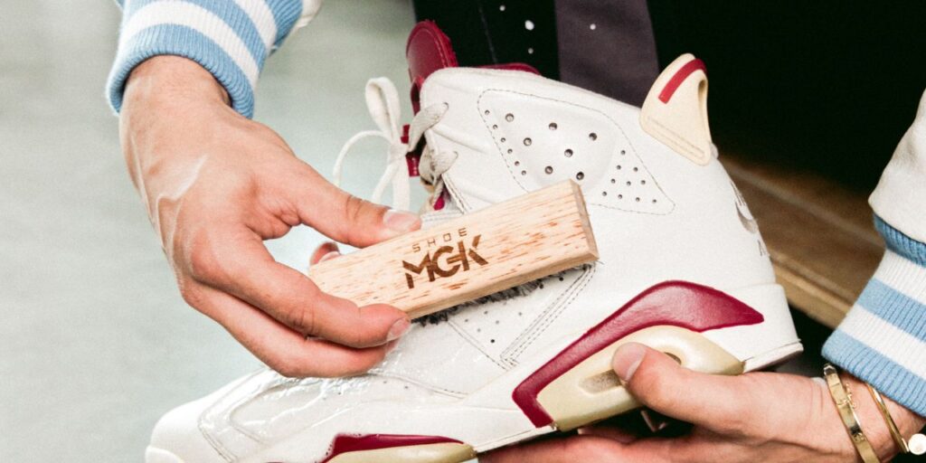 Man holds a Shoe MGK brush up against Nike Air Jordans