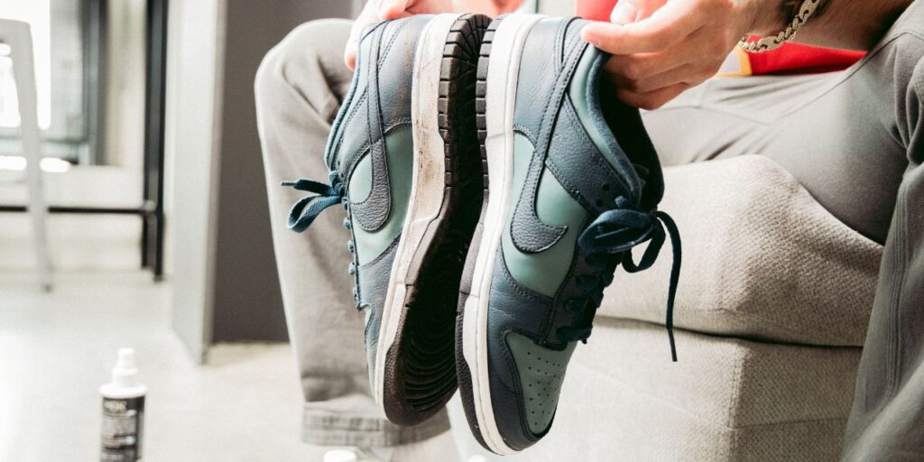Man holds a pair of Nike Dunks green and blue