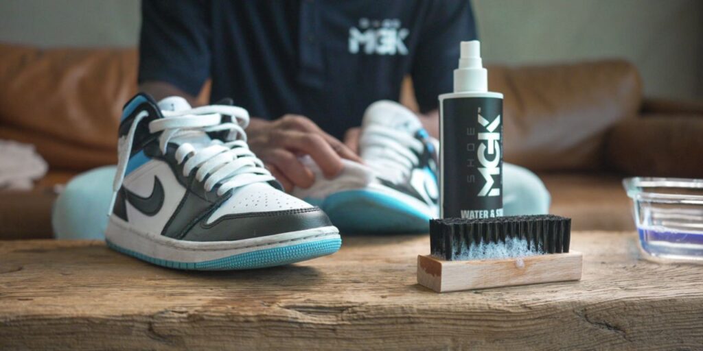 Air Jordan 1s next to a brush and a bottle of the Shoe MGK Water and Stain Repellent
