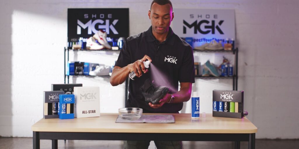 Man spraying black running shoes with the Shoe MGK Water and Stain Repellent