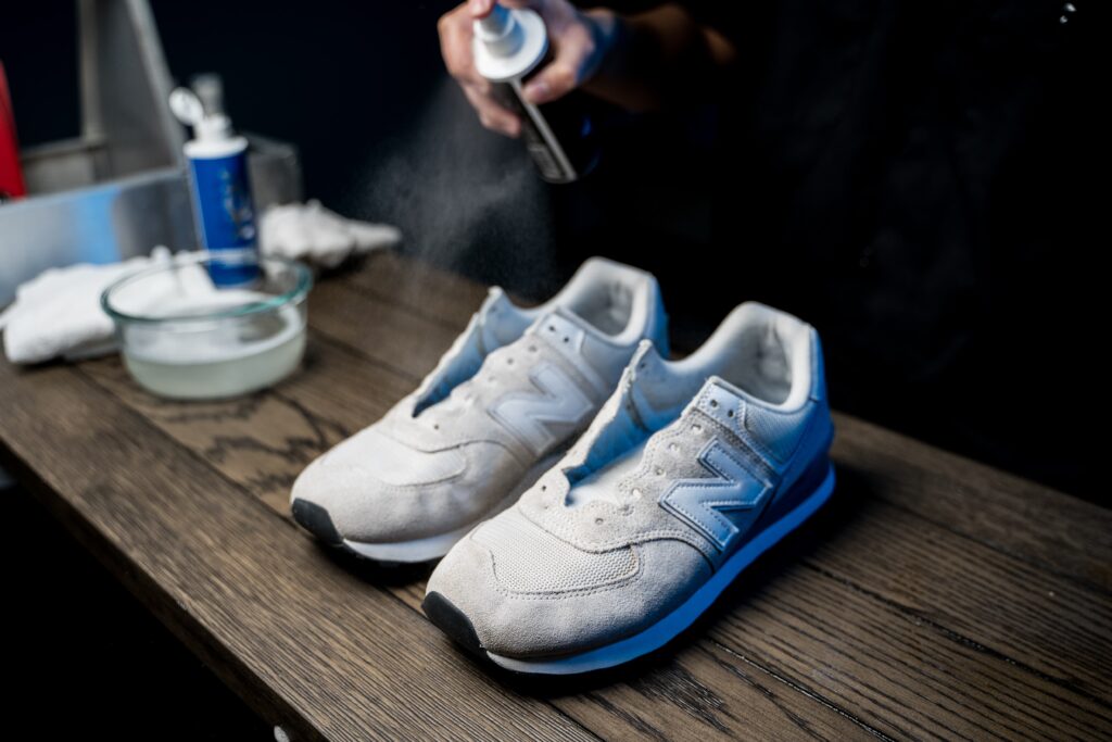 Man sprays New Balance 574 with the Shoe MGK Clean & Protect Kit