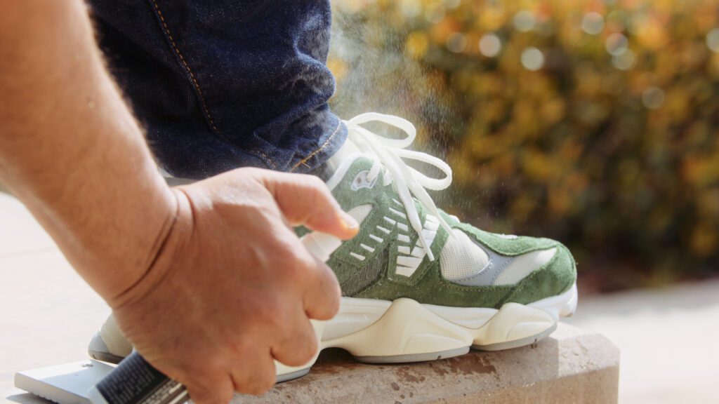 Man sprays his summer shoes with the shoe mgk water and stain repellent