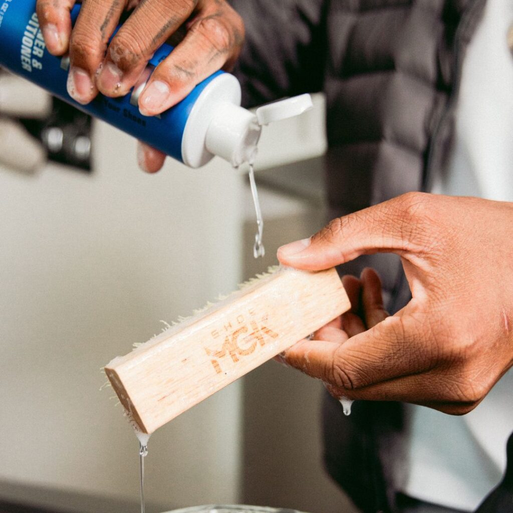 Man pours Shoe MGK Cleaner and Conditioner onto a shoe brush