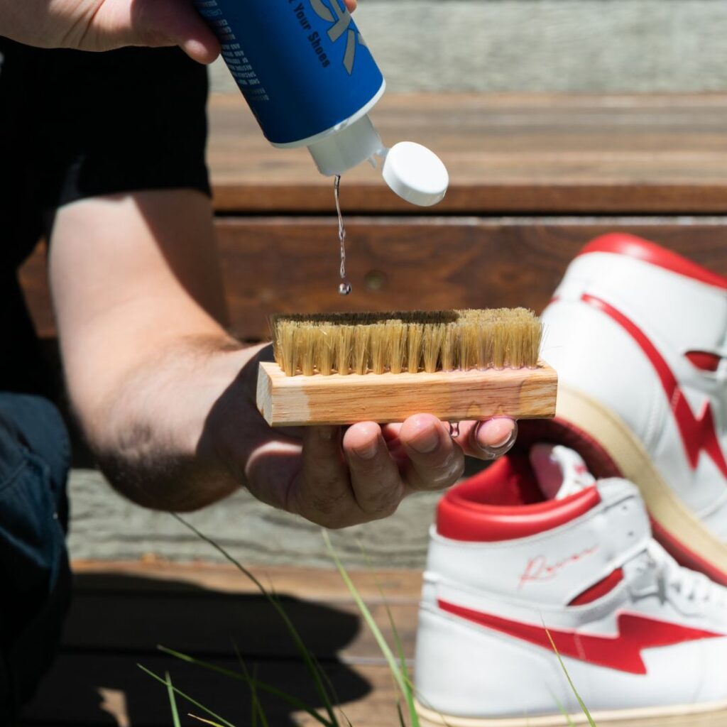 Man pours Shoe MGK Cleaner & Conditioner onto a shoe brush