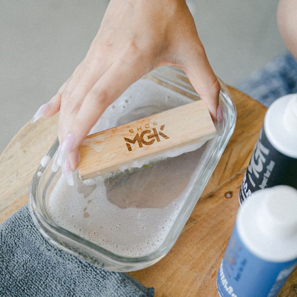 Man dips shoe brush into a bowl of water