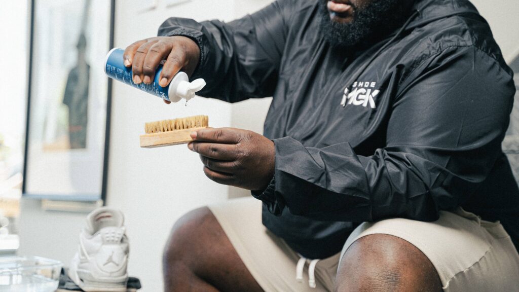 Man pours shoe mgk cleaner and conditioner onto a shoe brush