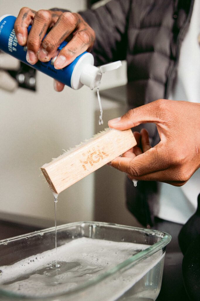 Man pours the Shoe MGK Cleaner and Conditioner onto a shoe brush