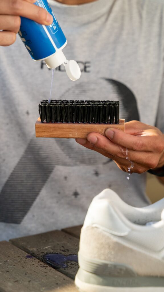 Man pours Shoe MGK Cleaner and Conditioner onto a shoe brush