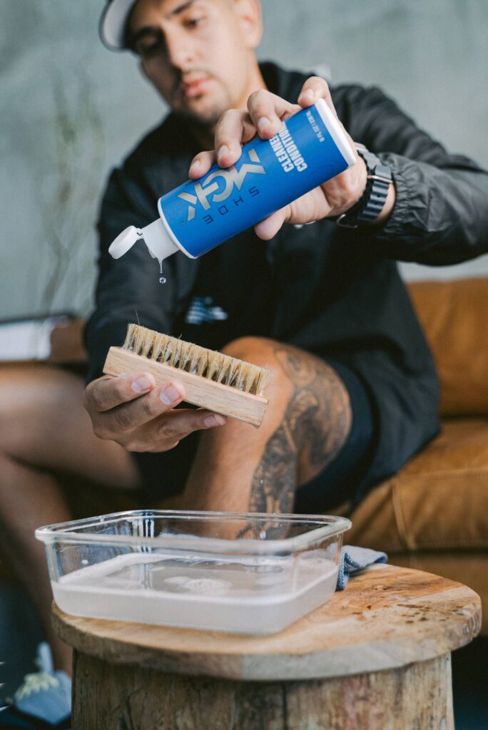 Man pours the Shoe MGK Cleaner and Conditioner onto a shoe brush