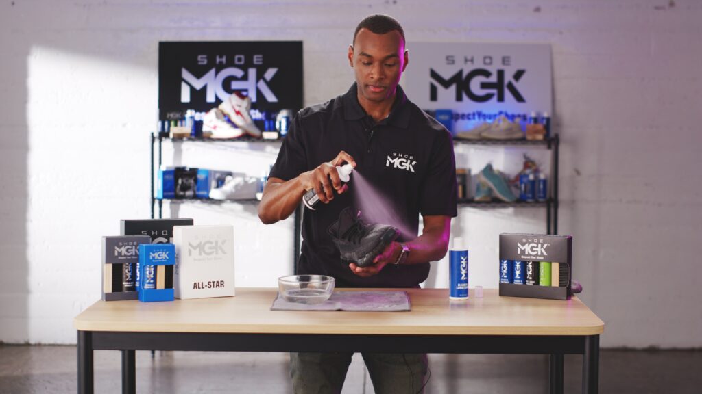 Man sprays shoes with the Shoe MGK water and Stain Repellent