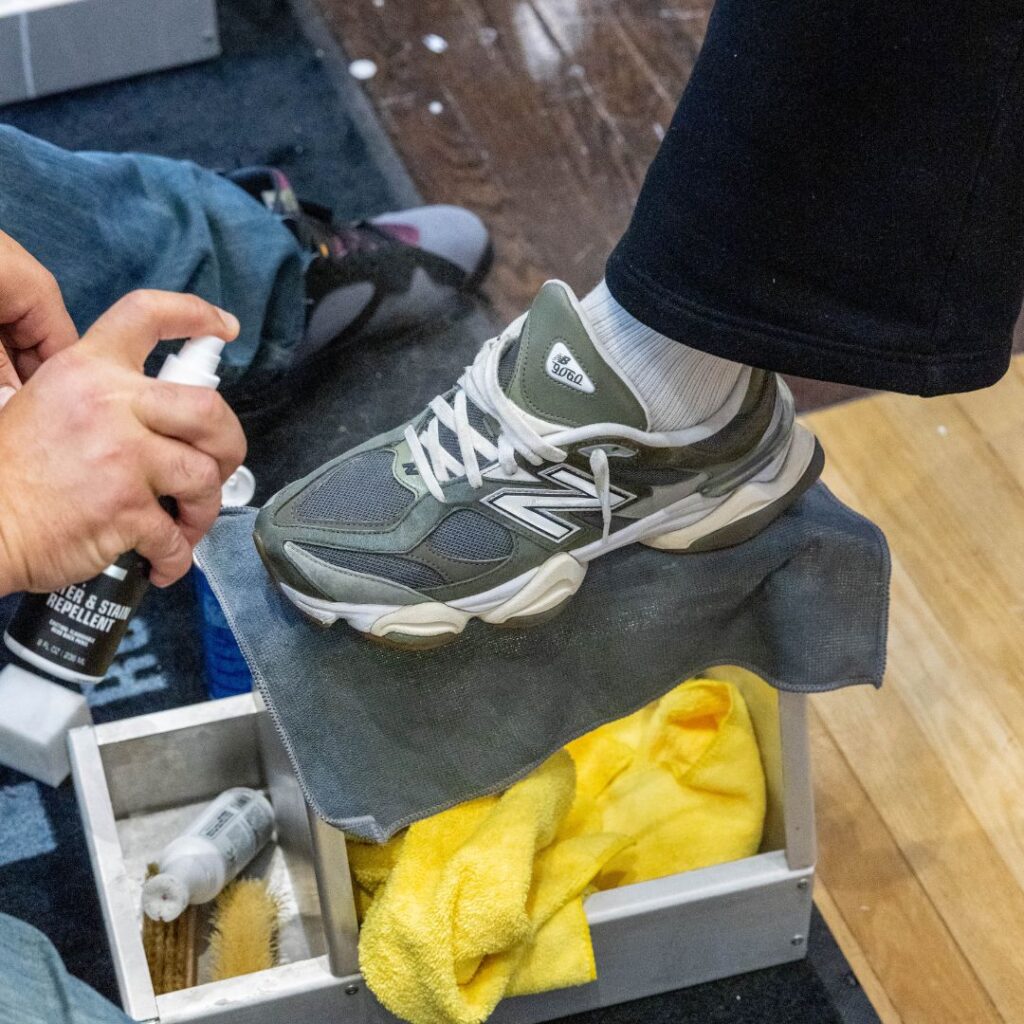 Man sprays shoes with the Shoe MGK Water and Stain Repellent