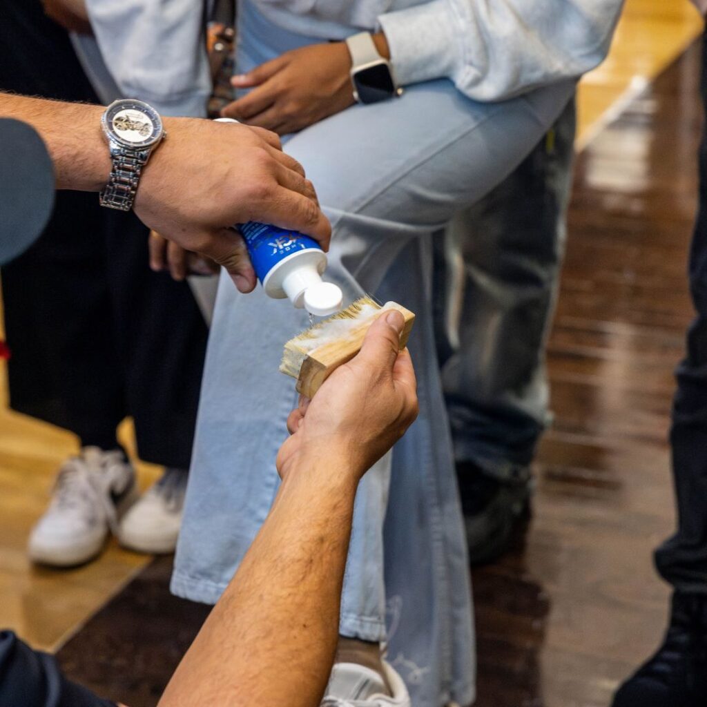 Man pours shoe cleaner onto a shoe brush