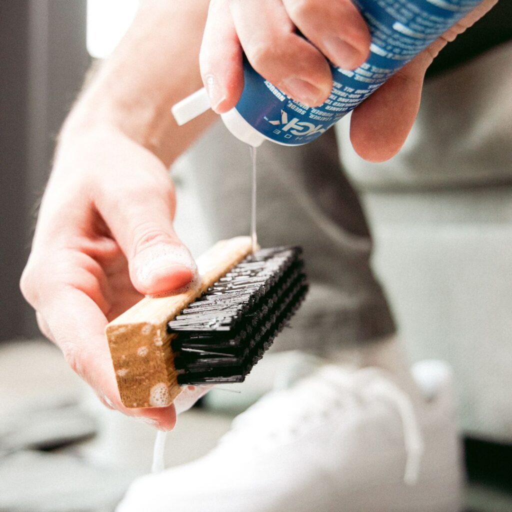 Man pours shoe mgk cleaner and conditioner onto a shoe brush