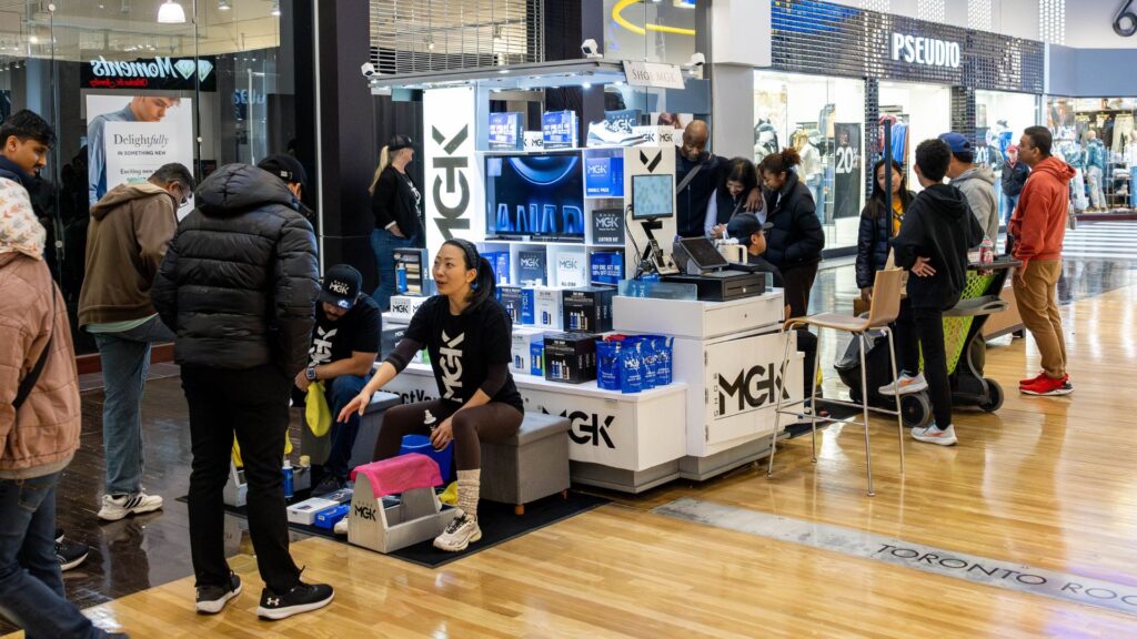 People cleaning shoes at a Shoe MGK Cart in a mall