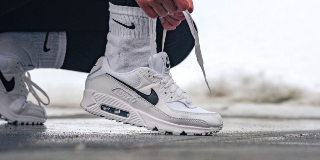 Woman ties white sneakers in the snow
