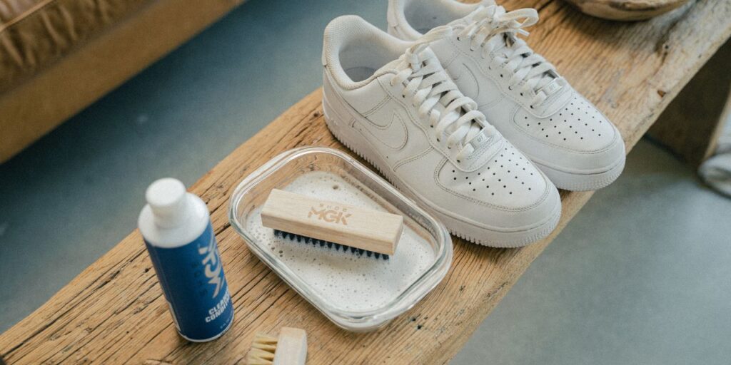 A pair of white shoes ready to be cleaned on a wooden bench